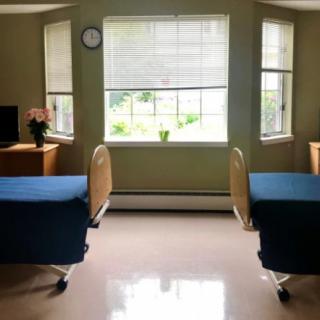 A well-lit hospital room with two beds and a large window.