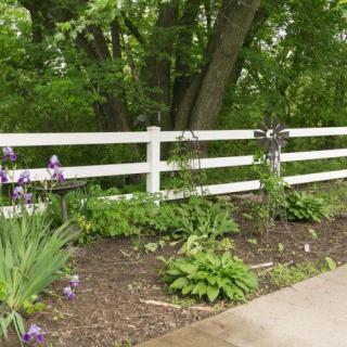 A serene garden scene with a white fence and blooming flowers.