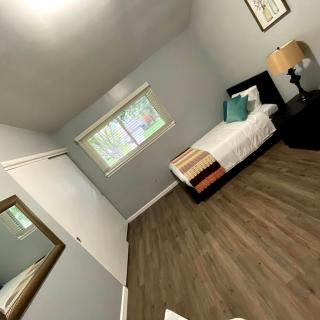 A minimalist bedroom with a single bed and hardwood flooring.