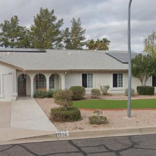 A suburban single-story house with a neatly maintained yard and solar panels on the roof.