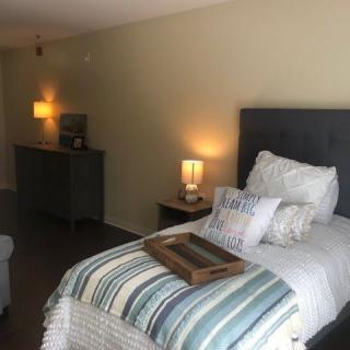 A cozy bedroom with a neatly made bed adorned with pillows and a decorative tray, softly lit by bedside lamps.