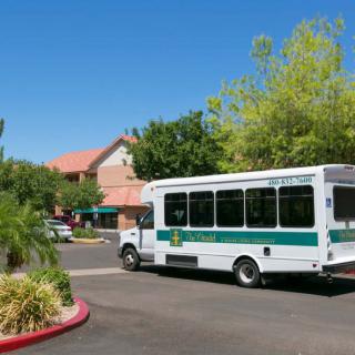 A shuttle bus driving through a parking lot on a sunny day.
