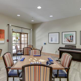 A well-appointed dining area featuring several tables and chairs, complemented by wall artwork and a piano in the corner.