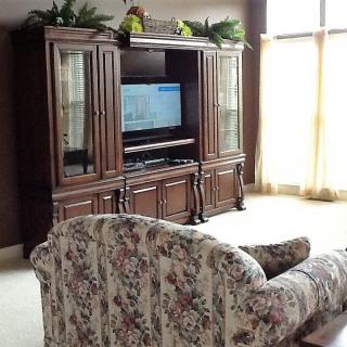 A traditionally styled living room featuring a floral sofa and a wooden entertainment center with a television.