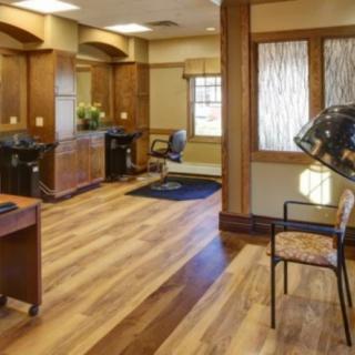 A cozy and well-organized hair salon with wood flooring and warm lighting.