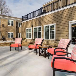 A sunny outdoor patio with comfortable chairs and a view of the building.