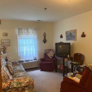 A cozy living room with a sofa and armchair, featuring a TV and various decorations.