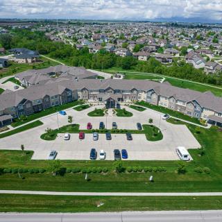 Aerial view of a large building with a parking lot surrounded by greenery and a residential area.