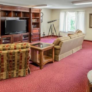 A cozy living room with comfortable seating, a large television, and a telescope by the window.