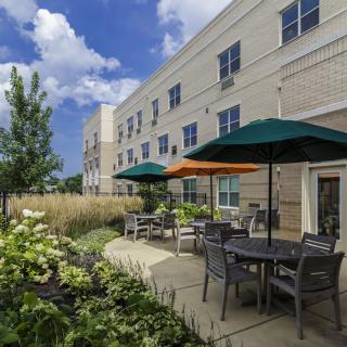 A scenic patio area outside an apartment complex with outdoor seating and colorful umbrellas.