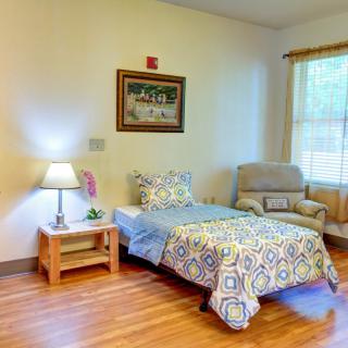 A cozy bedroom with a single bed, side table, and an armchair by the window.