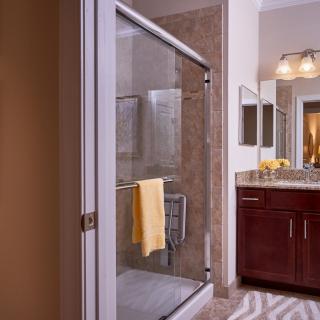 A modern bathroom featuring a glass-enclosed shower with a yellow towel and a sleek vanity with dual mirrors.