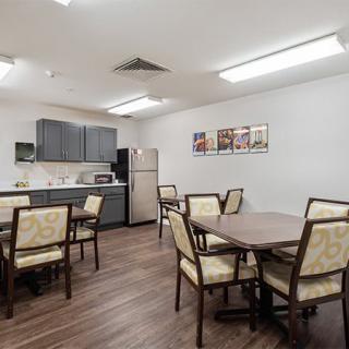 A modern dining area with multiple tables and chairs adjacent to a kitchen space.
