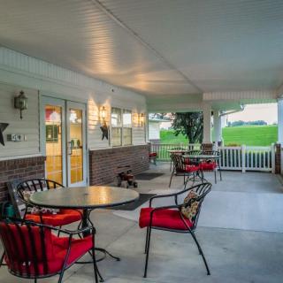 A cozy covered patio with tables and chairs, illuminated by warm lighting.