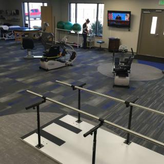 A modern rehabilitation center with exercise equipment and parallel bars for physical therapy.