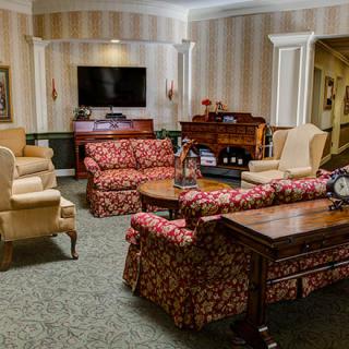 A cozy living room with patterned sofas, armchairs, and a television.