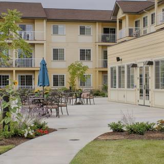 A view of a residential building with a landscaped patio and outdoor seating.