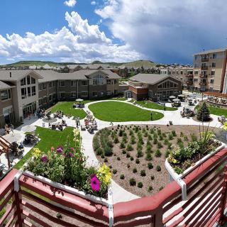A scenic view of a courtyard surrounded by residential buildings with a landscaped garden in the center under a cloudy sky.