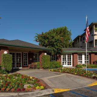 Entrance to a building with well-maintained landscaping and an American flag.