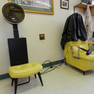 A vintage hair salon setup featuring a yellow chair and a hooded hairdryer.
