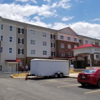 A view of a multi-story hotel building with parked vehicles in the foreground.