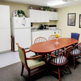A cozy and functional kitchen and dining area with a wooden table, chairs, white refrigerator, and cabinets.