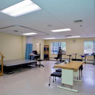 A spacious rehabilitation room equipped with therapy tables and exercise equipment.