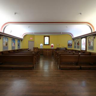 A serene interior view of a church, featuring wooden pews and vibrant yellow walls.