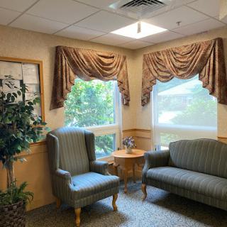 A cozy waiting area featuring comfortable seating, soft curtains, and natural light streaming in from the windows.