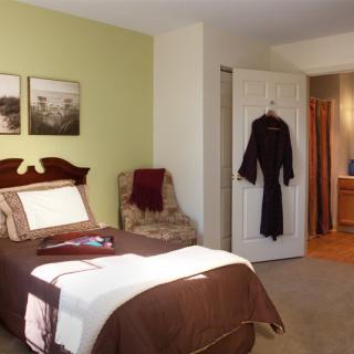 A cozy bedroom with a neatly made bed, an armchair, and soft lighting.