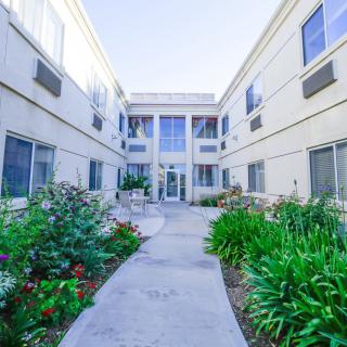 A view of an apartment complex with a garden pathway leading to the entrance.