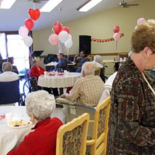A social gathering with seniors, featuring festive balloons and decorations.