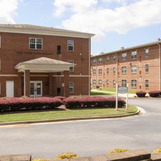 A brick residential building with a landscaped entrance and drive.