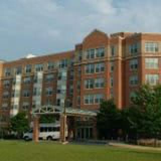 A large brick hotel building with multiple floors and a landscaped front entrance.