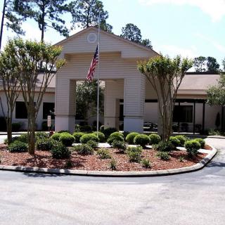 A well-maintained building with landscaped grounds and an American flag at the entrance.