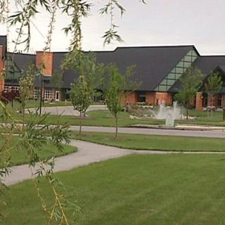 A modern building with a fountain on a landscaped lawn.
