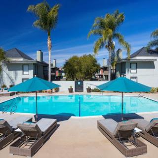 A serene poolside retreat featuring comfortable loungers and vibrant umbrellas under a clear blue sky.