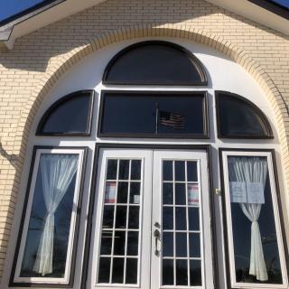 A front entryway with large glass doors and an arched window above, framed by a brick exterior.