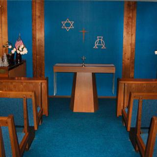 An interfaith chapel featuring an altar and symbols of Christianity and Judaism, with seating for visitors.