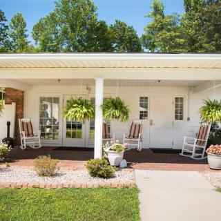 A cozy porch with rocking chairs and lush greenery creates a welcoming outdoor space.