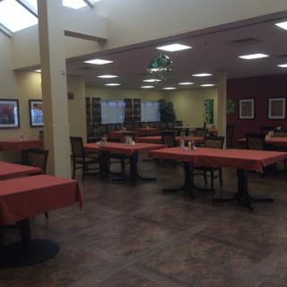 A quiet restaurant interior featuring empty tables with red tablecloths.