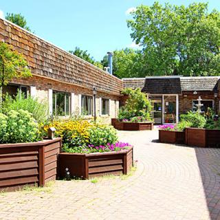 A serene courtyard featuring colorful flower beds and a well-maintained pathway, surrounded by rustic architecture.
