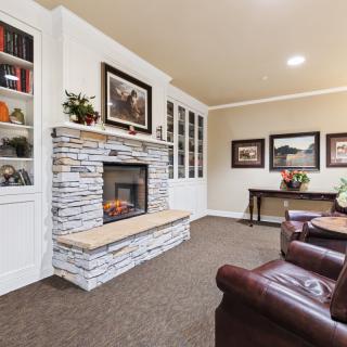 A cozy living room with a stone fireplace, leather armchairs, and built-in bookshelves.