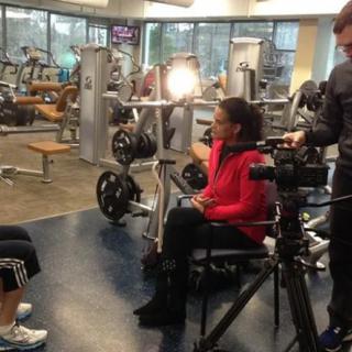 A camera crew conducting an interview in a gym setting.