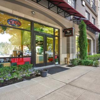 An inviting storefront with large windows and well-kept plants along the sidewalk.