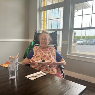 An elderly woman enjoying a meal in a cozy restaurant setting.