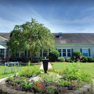 A beautiful garden with a central fountain in front of a house.