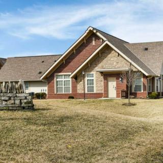 A suburban brick house with a well-maintained lawn under a blue sky.