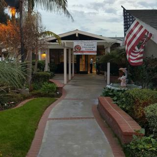 A pathway leading to the entrance of a building, adorned with an American flag and surrounded by a well-maintained garden.