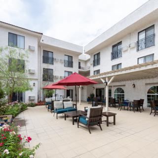 Outdoor patio area with seating and a red umbrella in front of a modern building.